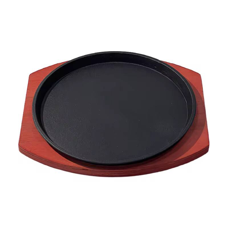 Cast iron hot sizzling plate on wooden tray