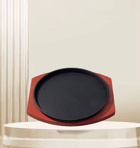 Cast iron hot sizzling plate on wooden tray