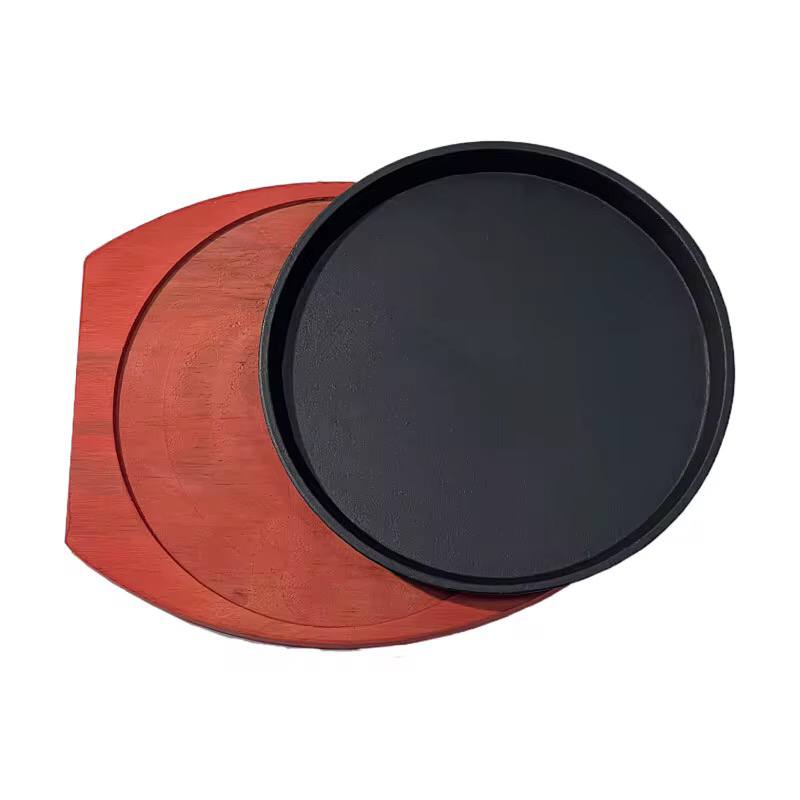 Cast iron hot sizzling plate on wooden tray